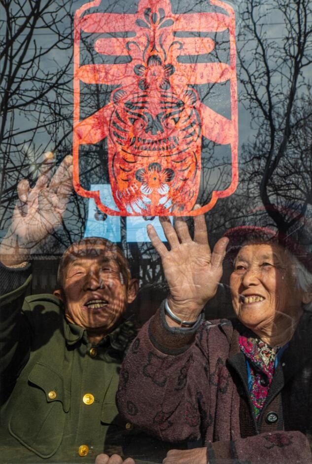 臘月里，霍州市師莊鄉(xiāng)馮南垣村村民師榮光(左)在災(zāi)后重建的新家里貼窗花。(霍州市委宣傳部供圖)