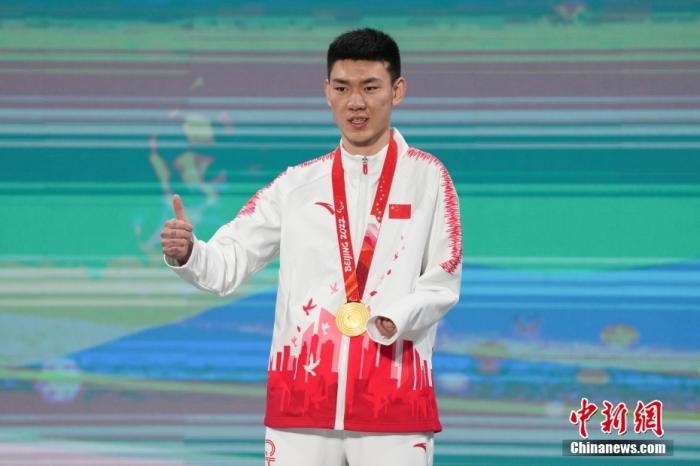 3月6日，梁景怡在延慶頒獎廣場領獎臺上豎起大拇指。當日，在國家高山滑雪中心舉行的北京2022年冬殘奧會殘奧高山滑雪男子超級大回轉—站姿決賽中，中國選手梁景怡奪得冠軍。 <a target='_blank' href='/'>中新社</a>記者 楊華峰 攝