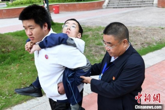 朱金祥背著鐘華強(qiáng)去教室上課的路上，也經(jīng)常碰到值班的校領(lǐng)導(dǎo)和老師前來搭把手。 卓忠偉 攝