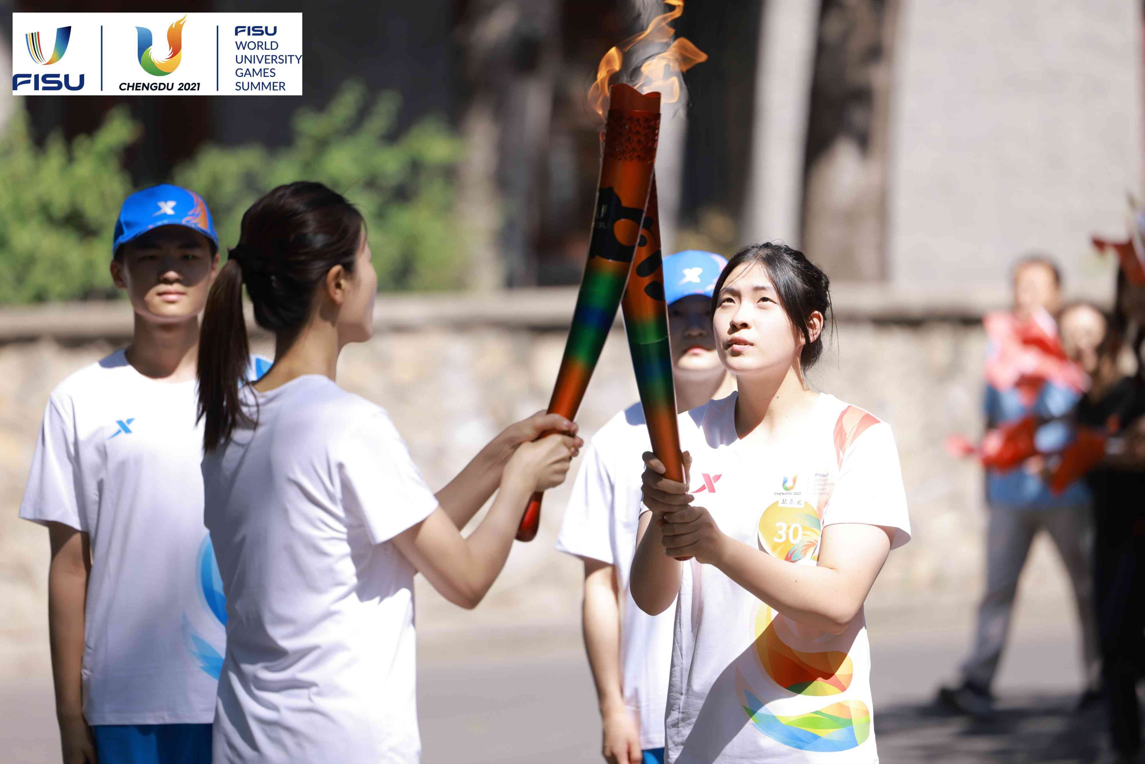 兩名大運(yùn)會(huì)火炬手進(jìn)行火炬?zhèn)鬟f。 圖片來(lái)源：成都大運(yùn)會(huì)執(zhí)委會(huì)供圖