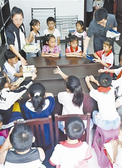  圖④：法院干警為留守兒童發(fā)放暑假讀物。