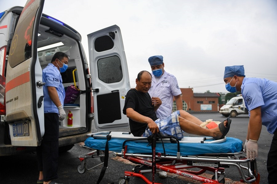 8月1日，在北京市門頭溝區(qū)妙峰山鎮(zhèn)妙峰山民族學(xué)校臨時(shí)安置點(diǎn)，北京急救中心工作人員在轉(zhuǎn)運(yùn)一名受傷村民。新華社記者 鞠煥宗 攝