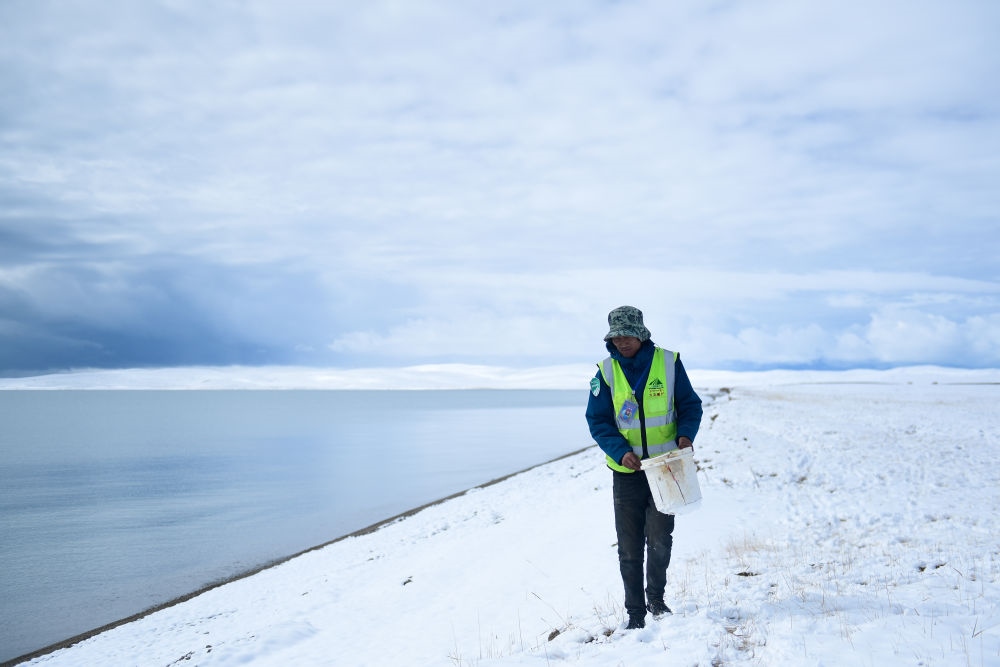 2021年10月20日，在青海省果洛藏族自治州瑪多縣扎陵湖鄉(xiāng)勒那村，三江源國家公園黃河源園區(qū)生態(tài)管護員在扎陵湖邊撿拾垃圾。新華社記者 張龍 攝