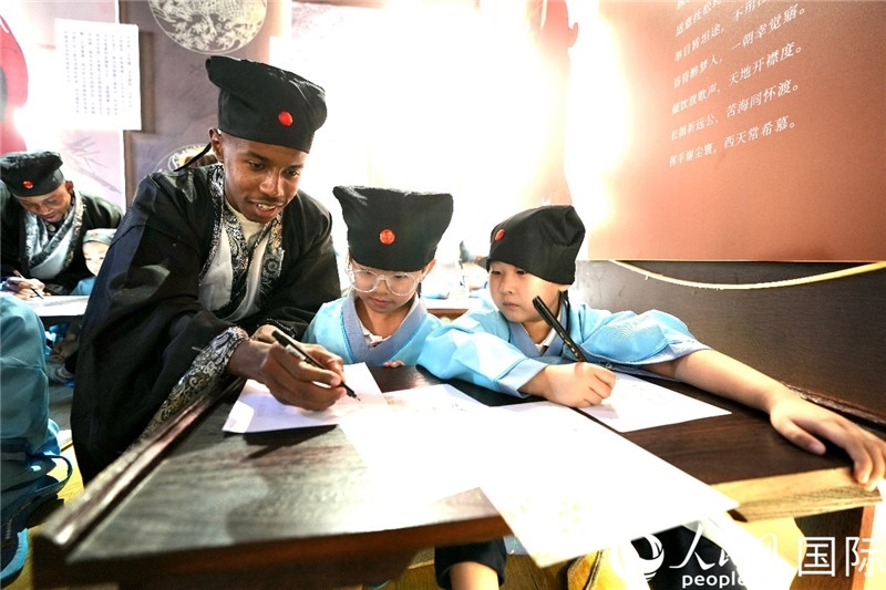 圖為選手與同學們一起寫書法。人民網 盧鵬宇攝