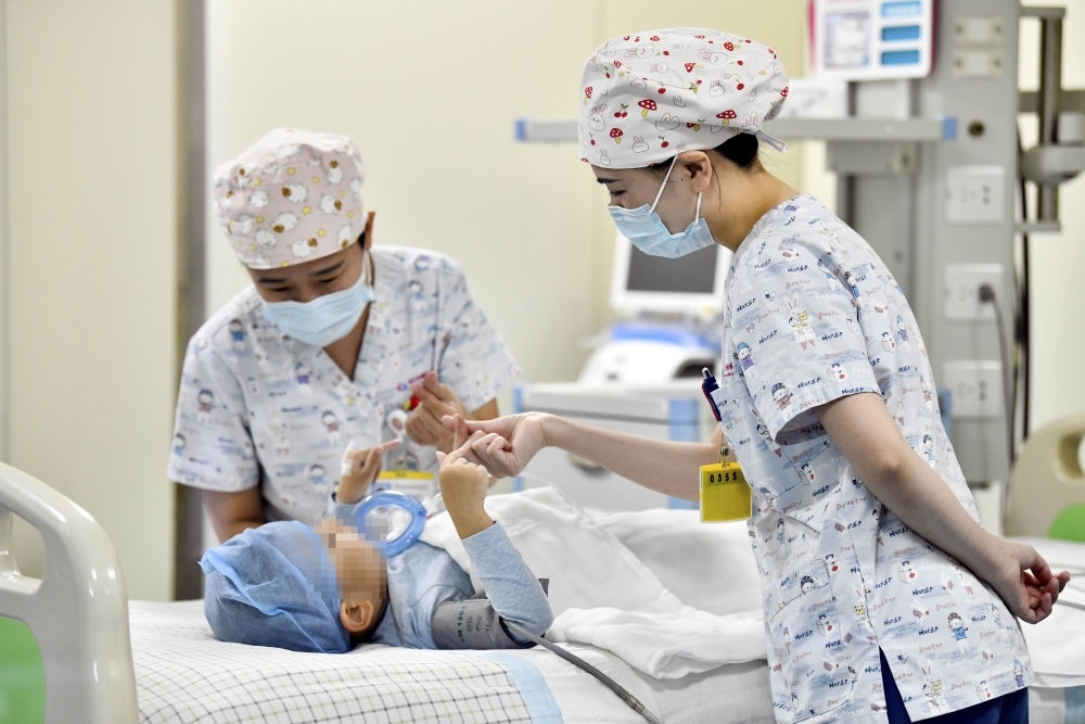 在山東省棗莊市婦幼保健院兒童ICU病房，醫(yī)護人員為完成靶向治療藥物諾西那生鈉的4歲脊髓性肌萎縮癥患兒加油鼓勁（2022年1月1日攝）。諾西那生鈉注射液是我國首個獲批治療脊髓性肌萎縮癥的進口藥物，2019年進入中國市場時，每針價格近70萬元。在2021年國家醫(yī)保目錄藥品談判中，以3.3萬元每針的價格進入新版醫(yī)保藥品目錄。新華社記者 郭緒雷 攝