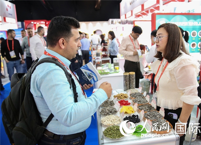 圖為一家中國(guó)干果參展企業(yè)代表與采購(gòu)商洽談。人民網(wǎng) 塔里克·易卜拉欣攝