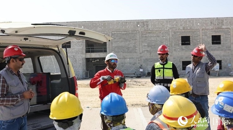 穆薩瓦爾(圖中紅衣人）現(xiàn)場演示工具操作規(guī)范。人民網(wǎng)記者 管克江攝