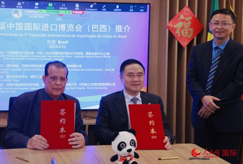 巴西外貿商會聯合會會長阿代爾·羅伯托（左）與中國國際進口博覽局副局長吳政平（中）現場簽訂協(xié)議。人民網記者 宋亦然攝