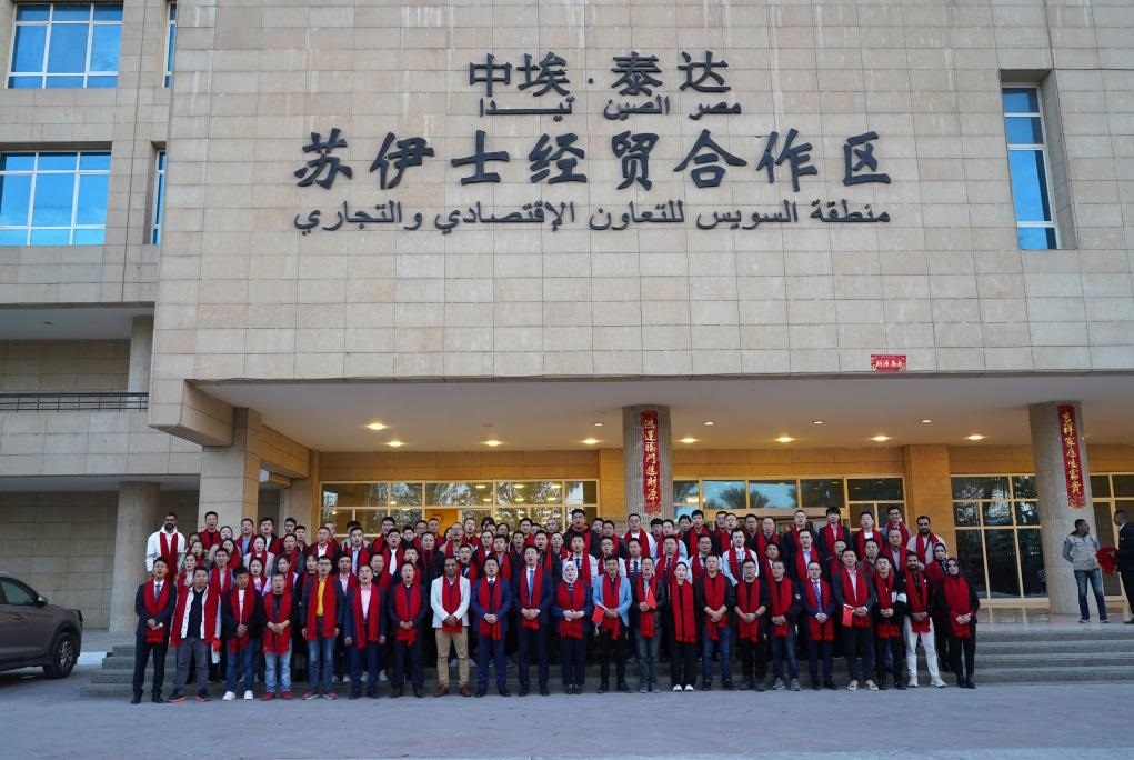 2024年2月11日，在位于埃及蘇伊士省的中?！ぬ┻_(dá)蘇伊士經(jīng)貿(mào)合作區(qū)，中埃員工在合作區(qū)辦公大樓前合影拜年。新華社發(fā)（泰達(dá)合作區(qū)供圖）
