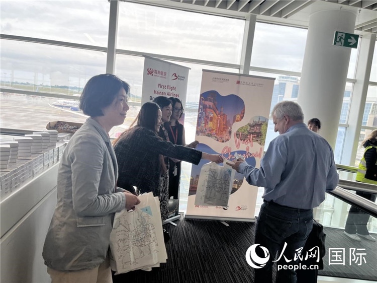 圖為工作人員向乘客發(fā)放復航首班禮物。 牛瑞飛攝