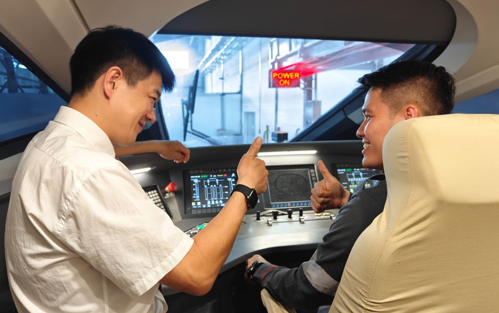 2023年8月25日，在印度尼西亞萬隆的雅萬高鐵德卡魯爾動車所內(nèi)，中國師傅穆振（左）向印尼火車司機(jī)塞蒂亞萬講解動車組出庫前的上電作業(yè)。新華社記者 徐欽 攝