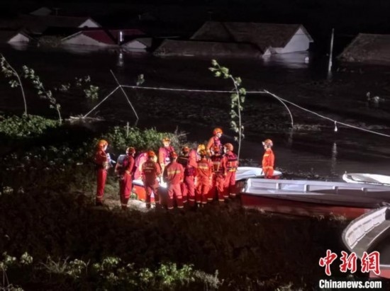  7月6日凌晨3時(shí)，在湖南岳陽(yáng)華容縣團(tuán)洲垸洞庭湖一線堤防，救援人員剛剛完成一次救援任務(wù)，遠(yuǎn)處是被淹的民房。中新社記者 白祖偕 攝