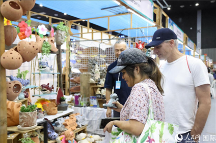 游客在蘭納博覽會特色展位上選購工藝品。人民網(wǎng)記者楊一攝