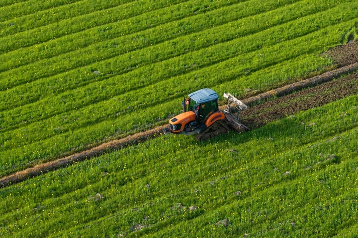 2024年3月19日，在湖南省常德市鼎城區(qū)謝家鋪鎮(zhèn)港中坪村，村民駕駛農(nóng)機翻耕田地（無人機照片）。新華社記者 陳思汗 攝
