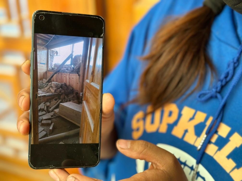 圖為7月17日拉毛東智在手機(jī)上找出地震后房屋受損的照片。新華社記者 張子琪 攝