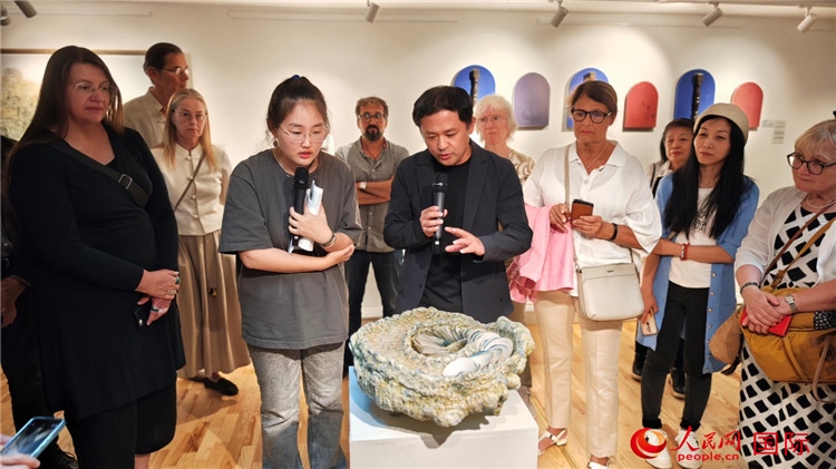 參展人、景德鎮(zhèn)陶瓷大學(xué)設(shè)計(jì)藝術(shù)學(xué)院副院長(zhǎng)余劍峰（中）向來(lái)賓介紹參展作品。人民網(wǎng)記者 殷淼攝