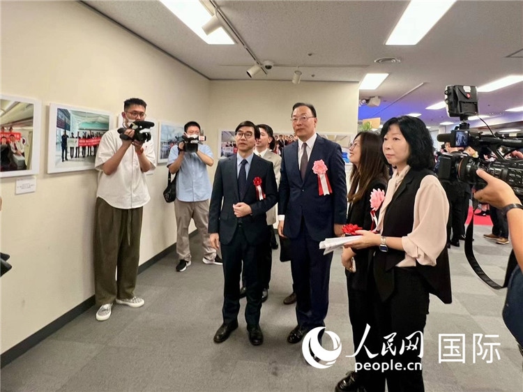 中國國際航空日韓地區(qū)支社支社長馮力為中國駐日本大使館臨時代辦施泳等嘉賓介紹展出圖片。人民網 許可攝