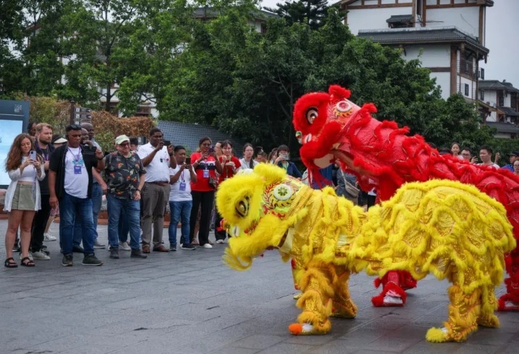 2024“一帶一路”媒體合作論壇聯(lián)合采訪調(diào)研行成員在樂山蘇稽古鎮(zhèn)觀看非遺舞獅表演。本報(bào)記者 伊霄攝