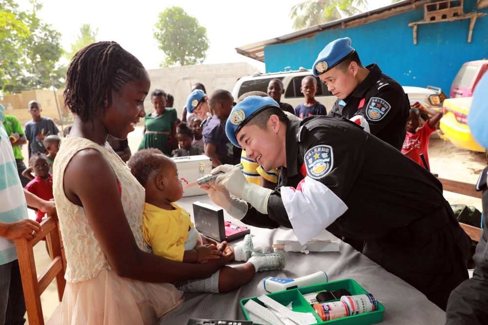 2017年12月28日，在利比里亞蒙羅維亞，中國維和警察防暴隊醫(yī)療人員為兒童做口腔檢查。