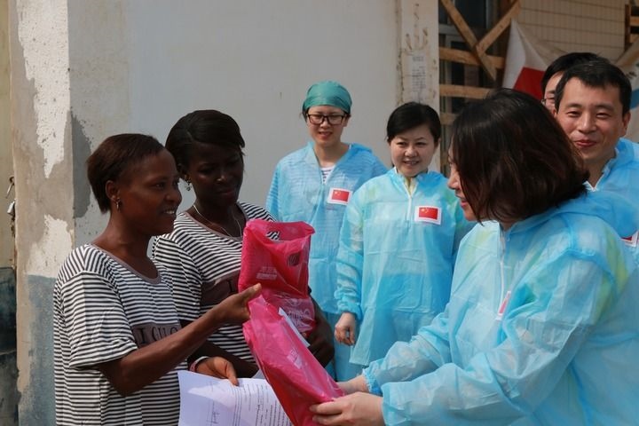 2015年4月4日，在位于塞拉利昂首都弗里敦市郊的中塞友好醫(yī)院埃博拉診療中心，中國(guó)第四批援塞醫(yī)療隊(duì)副隊(duì)長(zhǎng)邵蔚（右前）向被治愈的埃博拉出血熱患者贈(zèng)送禮物。新華社發(fā)（祖榮強(qiáng) 攝）