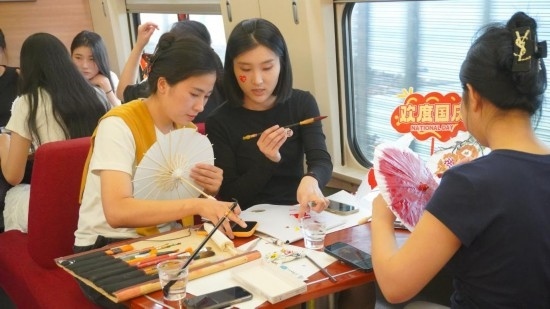 10月1日，旅客們在G1634次列車上給油紙傘作畫。新華社記者周義 攝