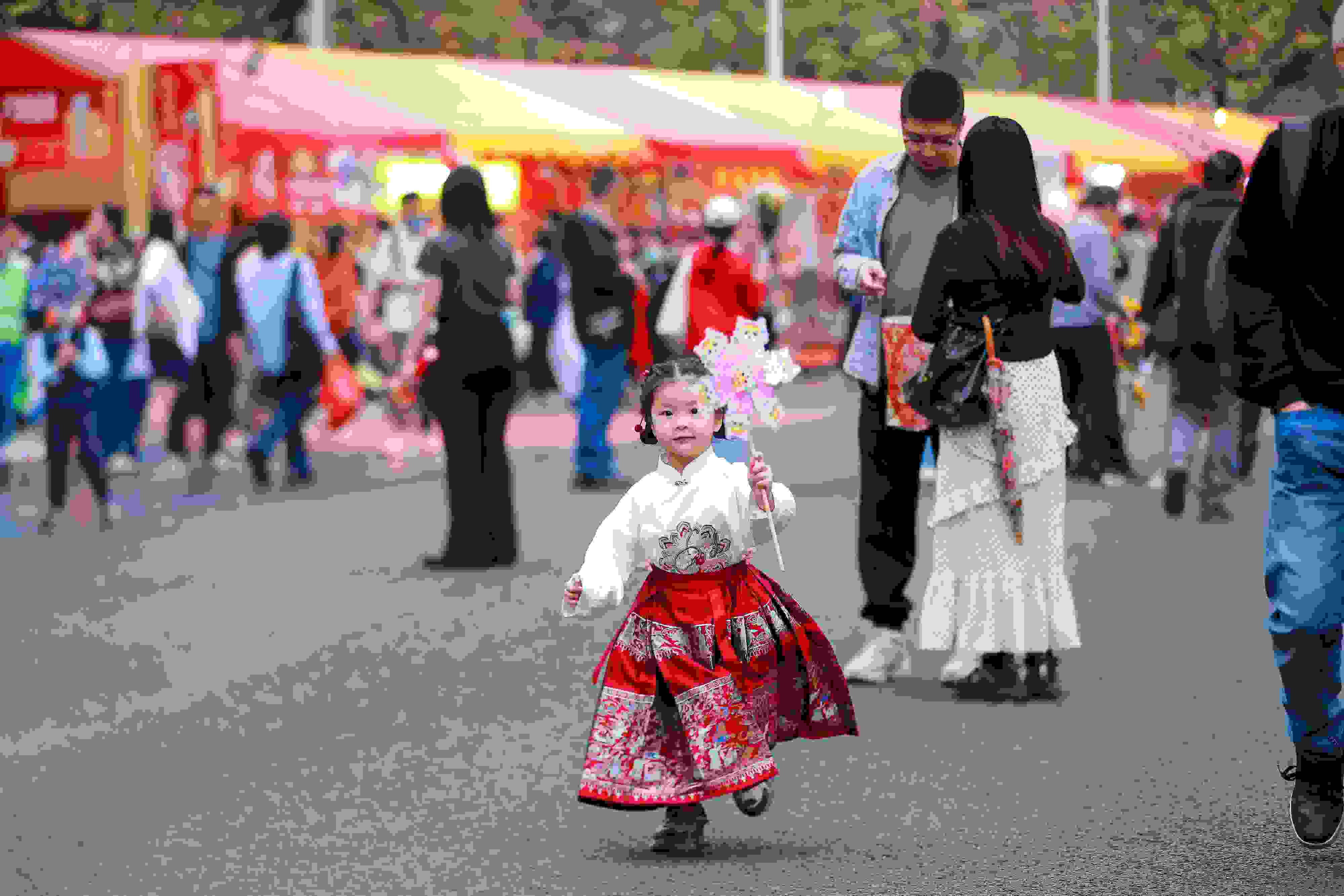 拿著風車穿著馬面裙的小女孩在廣州的花市上開心奔跑。