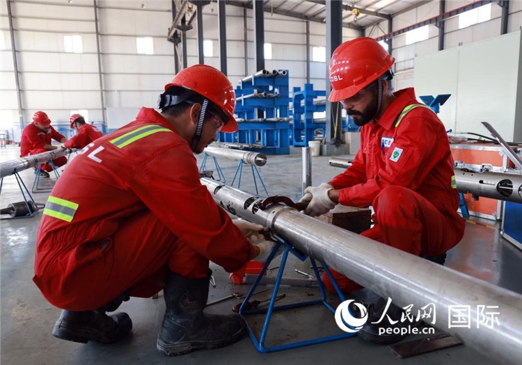 中伊員工共同在檢修鉆井設備。人民網(wǎng)記者管克江攝