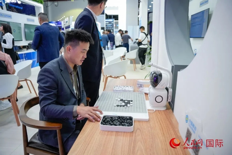 觀眾在中國移動國際有限公司展臺體驗智慧圍棋機器人。人民網(wǎng) 塔里克·易卜拉欣攝
