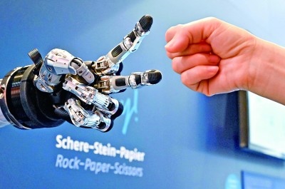在德國漢諾威工博會上，參觀者與一款智能機器人進(jìn)行“石頭剪子布”游戲。新華社發(fā)