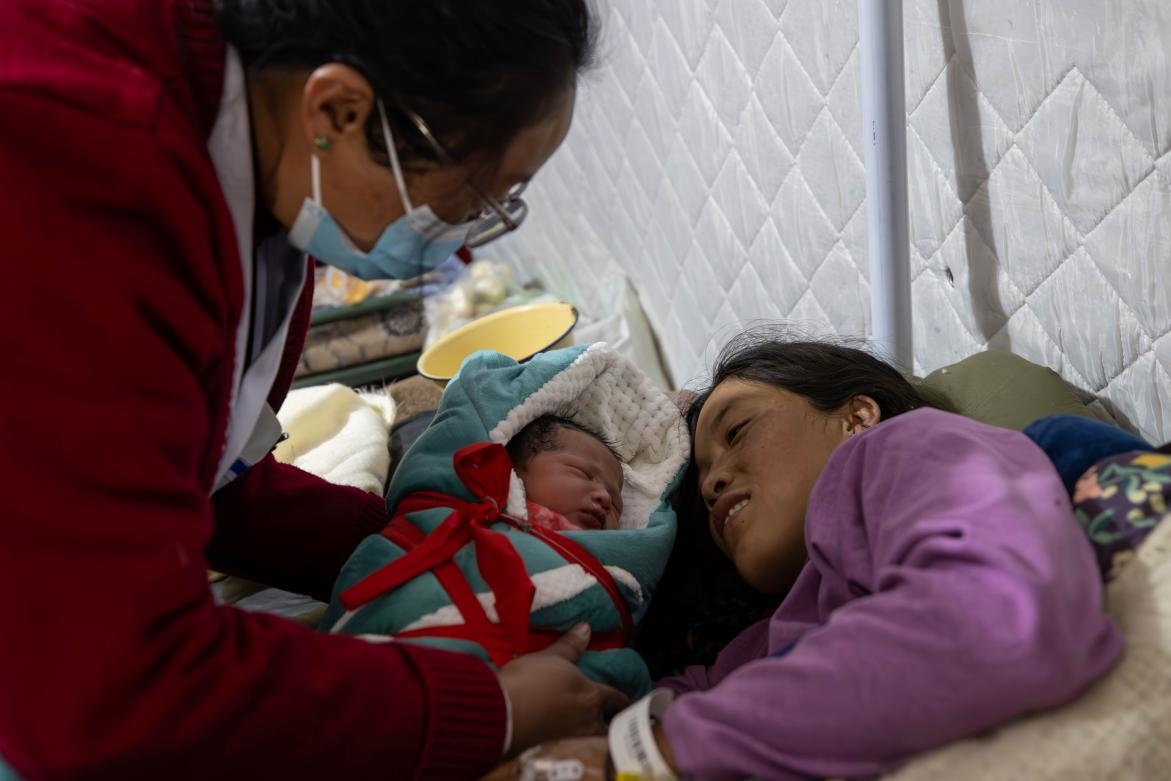 1月10日，定日縣中心醫(yī)院的婦產(chǎn)科醫(yī)生悉心照看一位母親和她懷里的新生兒。人民日?qǐng)?bào)記者張武軍攝