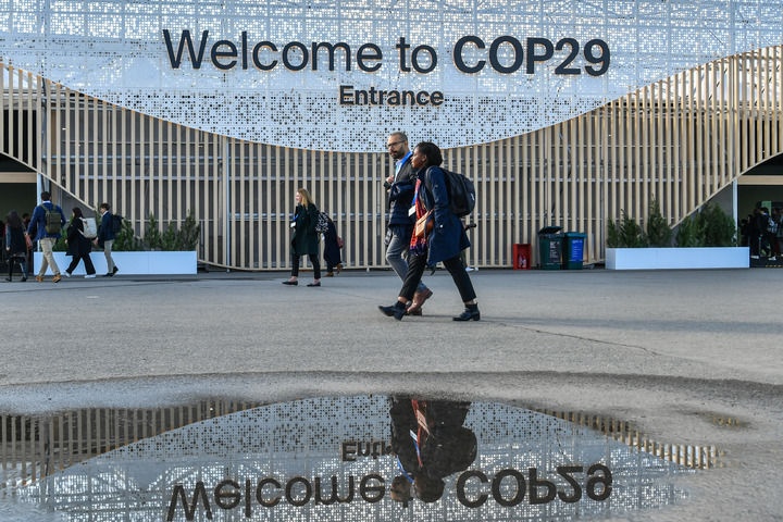 2024年11月15日，在阿塞拜疆首都巴庫(kù)，人們經(jīng)過(guò)聯(lián)合國(guó)氣候變化巴庫(kù)大會(huì)的會(huì)場(chǎng)。新華社記者 曹陽(yáng) 攝