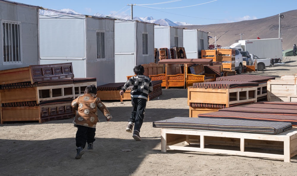 2025年1月13日，在定日縣嘎旦村，兩個孩子在剛運來的兩排藏床間奔跑。新華社記者丁增尼達 攝