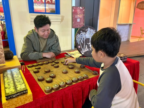 柯秋楓與市民下椰雕象棋。人民網(wǎng) 陳葉欣攝