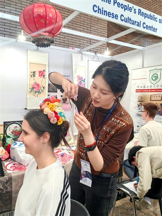 展覽正值羅馬尼亞迎春花節(jié)，國(guó)際中文教師志愿者潘婧穎向游客們介紹了國(guó)家非物質(zhì)文化遺產(chǎn)——福建泉州的簪花文化。布加勒斯特大學(xué)孔子學(xué)院供圖。