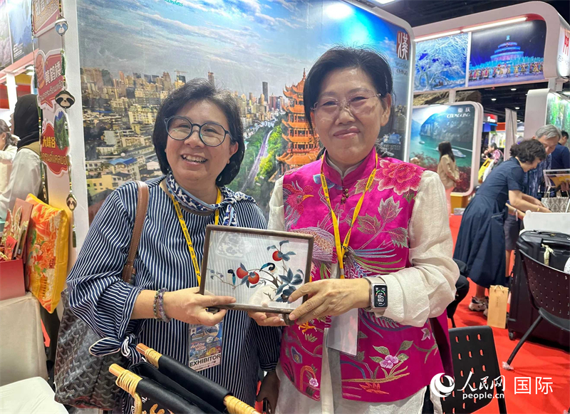 中國“大冶刺繡”傳承人劉小紅（右）參加泰國國際旅游展，向觀眾介紹中國非遺刺繡針法。人民網(wǎng)記者 簡承淵攝