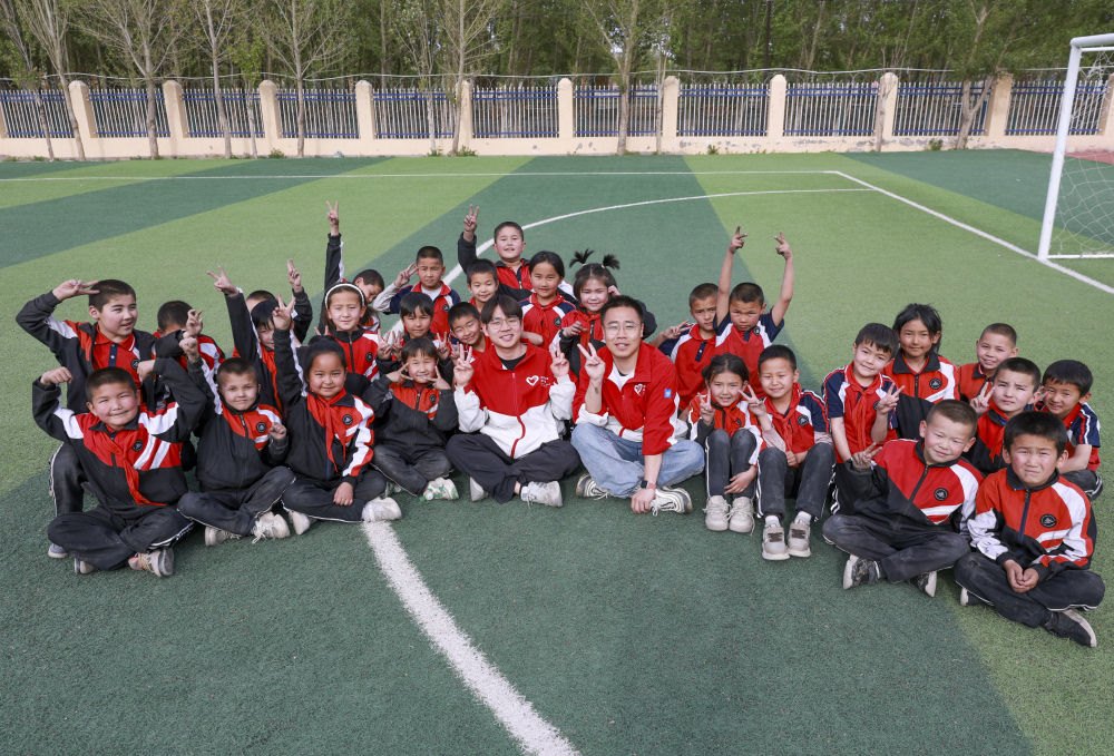 4月23日，在新疆克州阿圖什市哈拉峻鄉(xiāng)謝依特小學(xué)，支教教師王俊文（中左）、李軻凡（中右）和學(xué)生在一起。