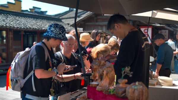 “五一”期間，游客正在烏鎮(zhèn)“水鄉(xiāng)碼頭”挑選購買文創(chuàng)產(chǎn)品。受訪者供圖