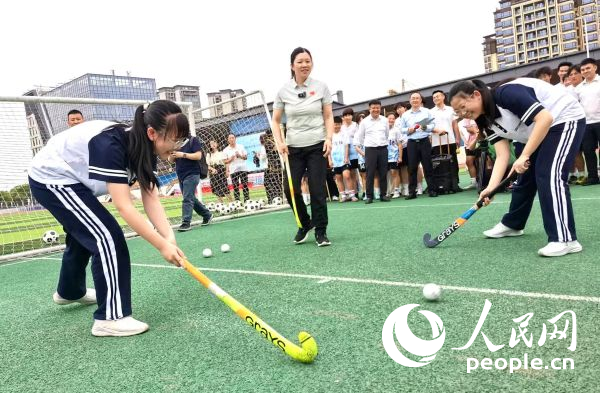 陳朝霞（中）指導學生體驗曲棍球。 人民網(wǎng)記者 楊磊攝